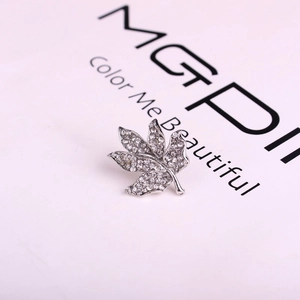 Broche en forme de feuille d'érable sertie de cristaux blancs sur base argentée