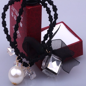 Elegant knotted hair tie with pearl, crystals, and black lace bow on a jewelry box