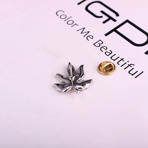 Détail macro d'une broche feuille d'érable argentée avec fermoir papillon doré