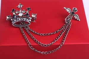 Detail of vintage crown and winged cross brooch with triple silver chains on red case