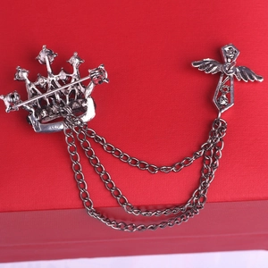 Close-up of vintage silver crown and cross lapel pin with tassel chains on red background