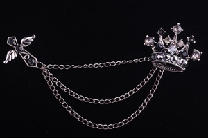 Detail of vintage silver crown and winged cross brooch with hanging metal tassels