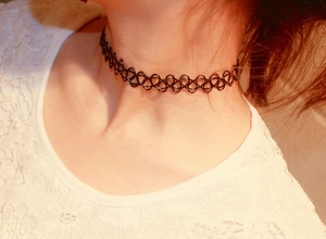 Nahaufnahme eines schwarzen elastischen Tattoo-Chokers mit Hohlwebmuster am Hals