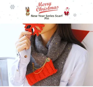 Vue détaillée de la broche couronne de Noël avec chaînes dorées sur une écharpe grise