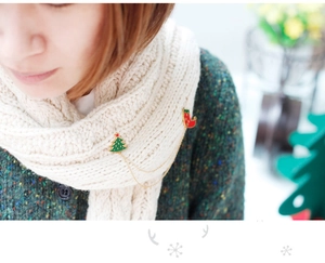 Détail de broches de Noël en émail avec chaîne sur une écharpe en maille blanche