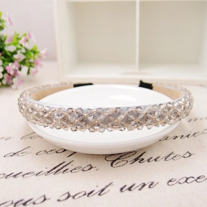 Close-up of handmade gray crystal beaded headband with gold accents on a white bowl