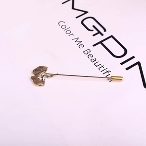 Macro detail of golden ginkgo leaf brooch showing textured veins and long safety pin