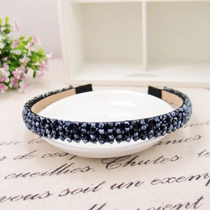 Macro shot of grey crystal beads on a handmade headband over a white decorative plate