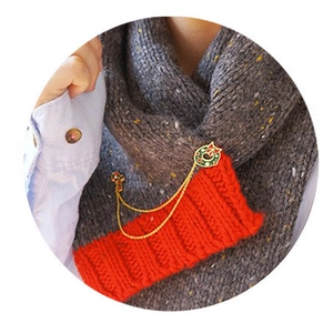 Détail d'une broche couronne de Noël avec nœud rouge et chaînes sur écharpe