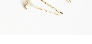 Gros plan de barrettes dorées en métal avec un design ondulé et motif coquillage