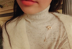 Detail of golden ginkgo leaf brooch pinned on a white knit sweater with leaf textures