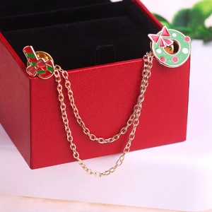 Détail de broche de Noël avec canne en sucre, couronne et chaînes dorées sur boîte rouge