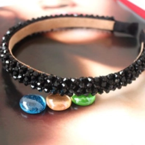 Elegant black beaded headband with four rows of faceted crystals on a fashion background