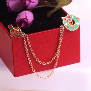 Détails de la broche couronne de Noël et chaussette avec chaîne dorée sur boîte cadeau rouge