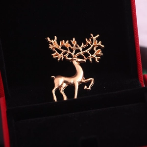 Gros plan d'une broche renne dorée aux bois détaillés dans un écrin à bijoux en velours noir