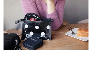 Gros plan sur une trousse de maquillage semi-transparente à pois noirs et blancs avec zip