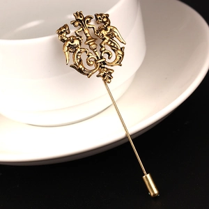 Vintage brass lion crest stick pin brooch for suits shown on a ceramic coffee cup edge