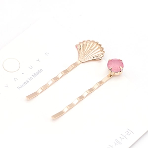 Ensemble de deux barrettes dorées avec un coquillage en métal et une pierre rose en cristal