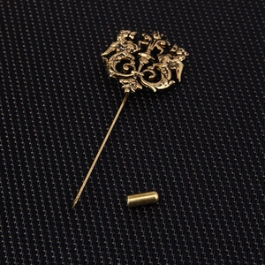 Vintage gold stick pin with floral relief and lion scrollwork on dark texture