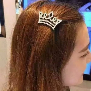 Eleganter silberner Kronen-Haarclip mit weißen Strasssteinen auf braunem welligem Haar