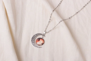 Macro detail of crescent moon pendant featuring a warm starry nebula glass cabochon