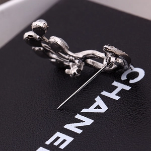 Macro detail of silver fashion brooch featuring secure back pin closure on black texture