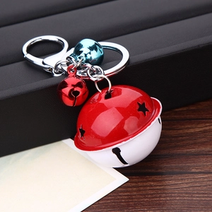 Detail view of multi-color metal bells keychain with star cutout on black leather and wood