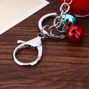 Detail of colorful bell charms and silver metal lobster clasp keychain on wood surface