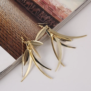 Dettaglio di orecchini pendenti a foglia dorata in stile boho con venature fini