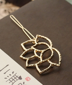 Detailed view of a golden metal lotus hair clip with exquisite hammered texture and zen style