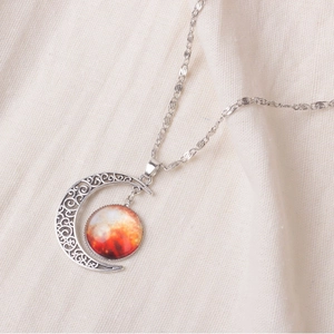 Starry sky moon pendant necklace with orange nebula gem on beige linen background