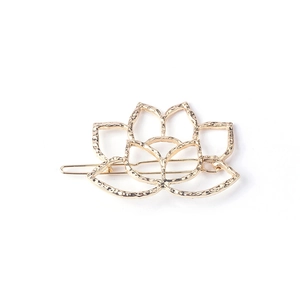 Elegant gold metal lotus flower hair clip with textured hammered finish on white backdrop