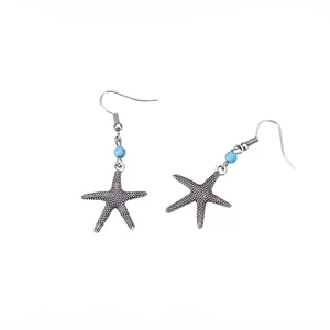 Détail de boucles d'oreilles étoile de mer rétro avec perles bleu ciel style marin