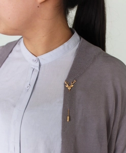 Détail d'une épingle de revers tête de cerf dorée vintage sur un cardigan gris chiné