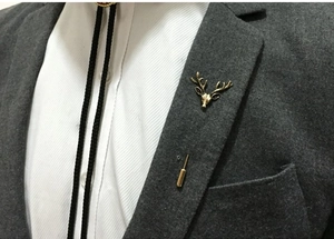 Détail d'une épingle de revers tête de cerf dorée sur une veste de costume grise