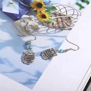Détail macro de boucles d'oreilles hibou vintage argenté avec perles turquoise sur magazine