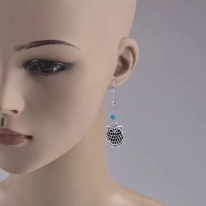 Gros plan de boucles d'oreilles hibou vintage argenté avec perle bleue