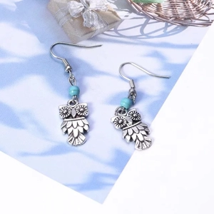 Détail de boucles d'oreilles hibou vintage avec perles turquoise sur fond décoratif