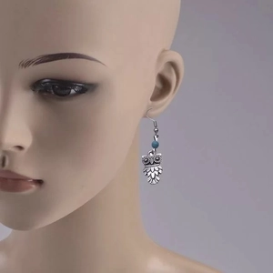 Vue détaillée des boucles d'oreilles hibou rétro avec perles turquoise et plumes