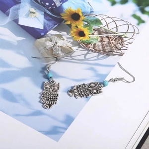Gros plan détaillé de boucles d'oreilles hibou rétro en argent avec perles bleues
