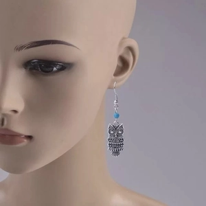 Détail de boucles d'oreilles hibou vintage avec perle bleue sur tête de mannequin
