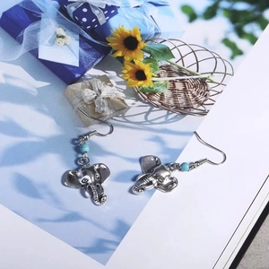Boucles d'oreilles éléphant vintage en argent avec perles de turquoise sur magazine