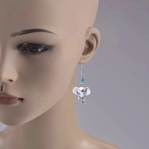 Détail des boucles d'oreilles éléphant argentées rétro avec perles turquoise sur modèle