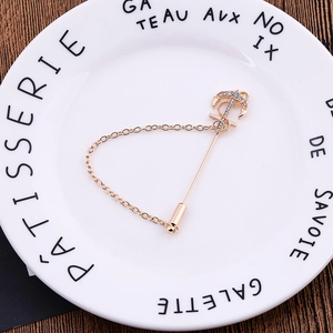 Golden anchor brooch with sparkling rhinestones and chain on a vintage background