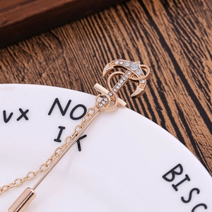Vintage golden anchor brooch with rhinestones and rope texture on decorative tray