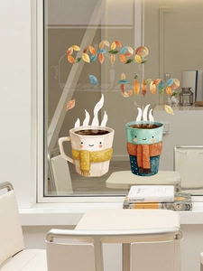 Detail of cute cartoon coffee cup stickers and autumn leaf lettering on a glass window