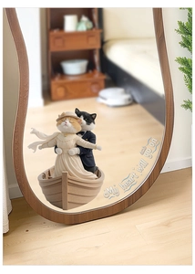 Titanic-inspired cat couple figurines in a wooden boat shown through a mirror reflection