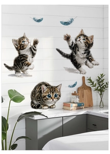 Close-up of adorable tabby kittens and blue feathers stickers on a wooden kitchen wall