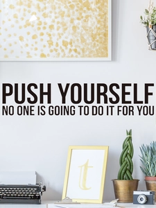 Close-up of black vinyl wall decal with motivational quote Push Yourself on white wall