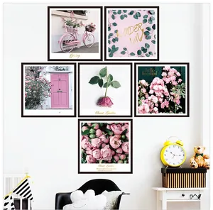 Set of 6 pink rose wall art prints with black frames in a cozy nursery room setting